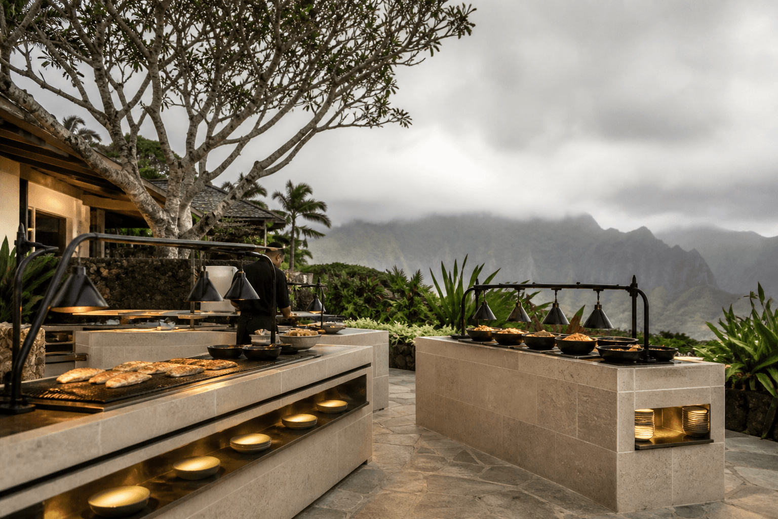 Hot stations on a Kauaʻi estate terrace — grilled fish, misted mountains, inquiry-scale.